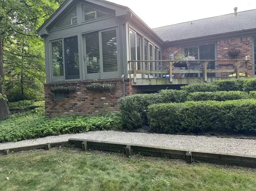 Trimmed hedges and a fresh gravel path beside a sunroom at a Troy, MI home